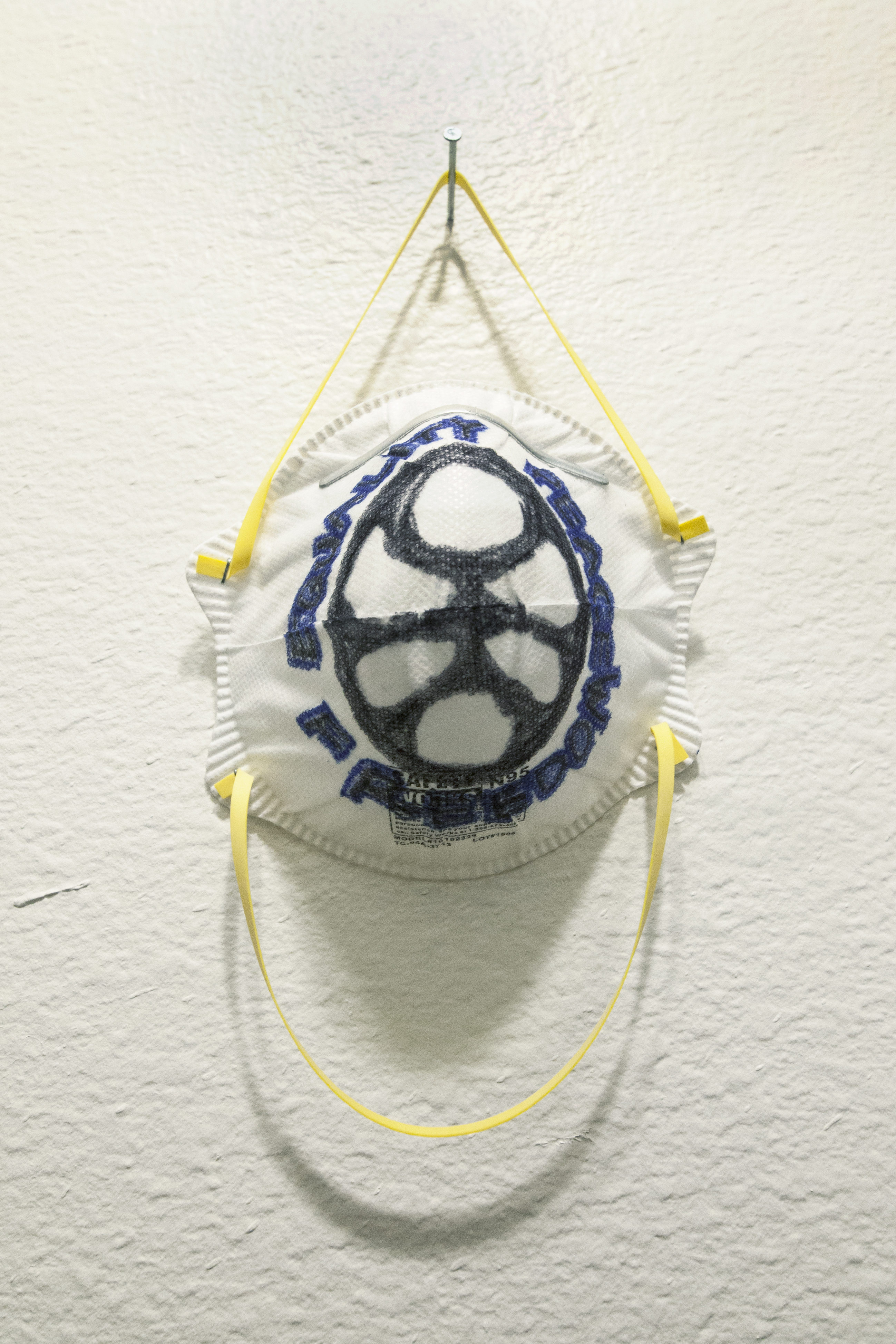 A resperator with a graphic logo drawn on it hung on a white wall